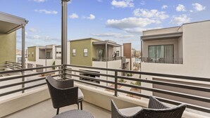 A balcony with wicker furniture and a view of modern buildings. - Villa #12 At Bloomington Country Club 4 Bedroom Townhouse (St. George)