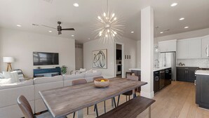 A modern living room with a large sofa, a dining table, and a kitchen in the background.