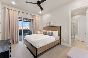 A bedroom with a bed, curtains, a ceiling fan, and a view through a glass door. - Villa #01 At Bloomington Country Club 3 Bedroom Condo (St. George)