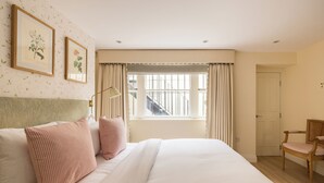 A neatly arranged bedroom with a large bed, a chair, and a window with curtains. - The Chelsea Abode - 4bdr Home With Terrace (London)