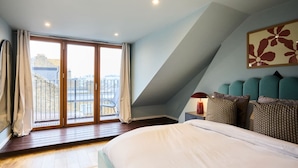A bedroom with a large bed, a balcony with a chair, and a city view. - The Kensal Green Hideout - Classy 2bdr Apartment (London)