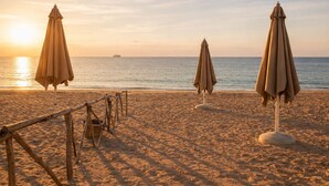 A beach with two umbrellas and a wooden fence. - Cozy Chalet With Stunning View  (Ataqah)