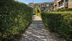 A pathway flanked by neatly trimmed hedges, leading to a building with multiple balconies and a modern architectural style. - Cozy Chalet With Stunning View  (Ataqah)