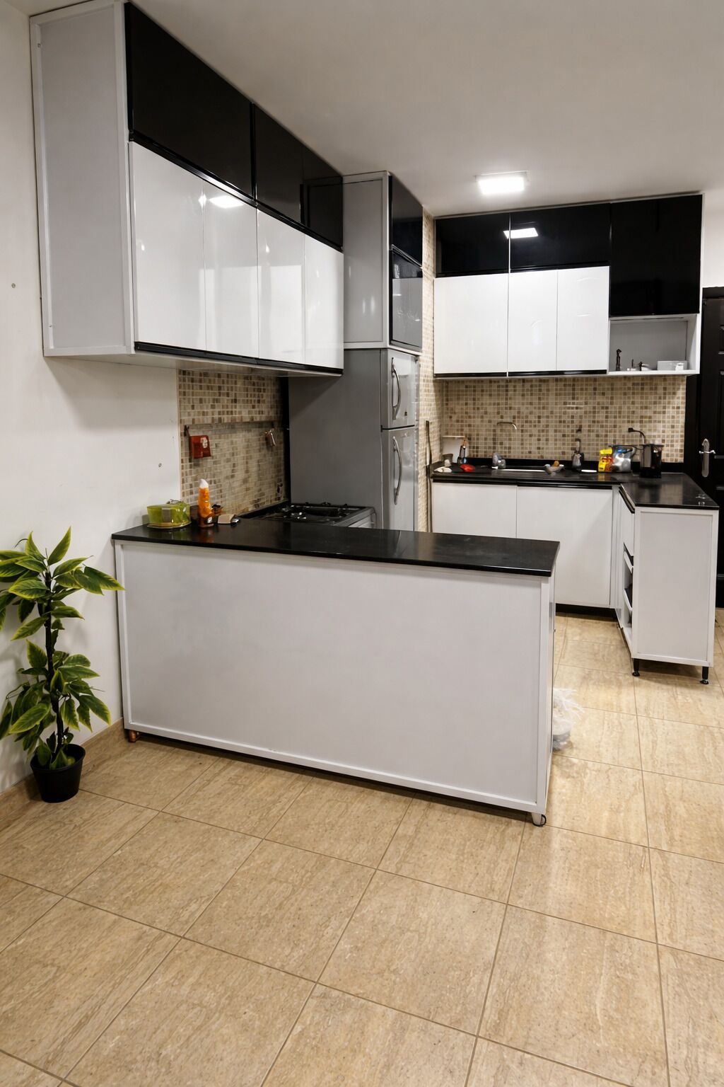 A modern kitchen with white cabinets, a black countertop, and a tiled backsplash.