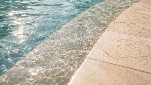 A clear swimming pool with a tiled edge, surrounded by lounge chairs and umbrellas, indicating a resort setting. - Cozy Chalet With Stunning View  (Ataqah)