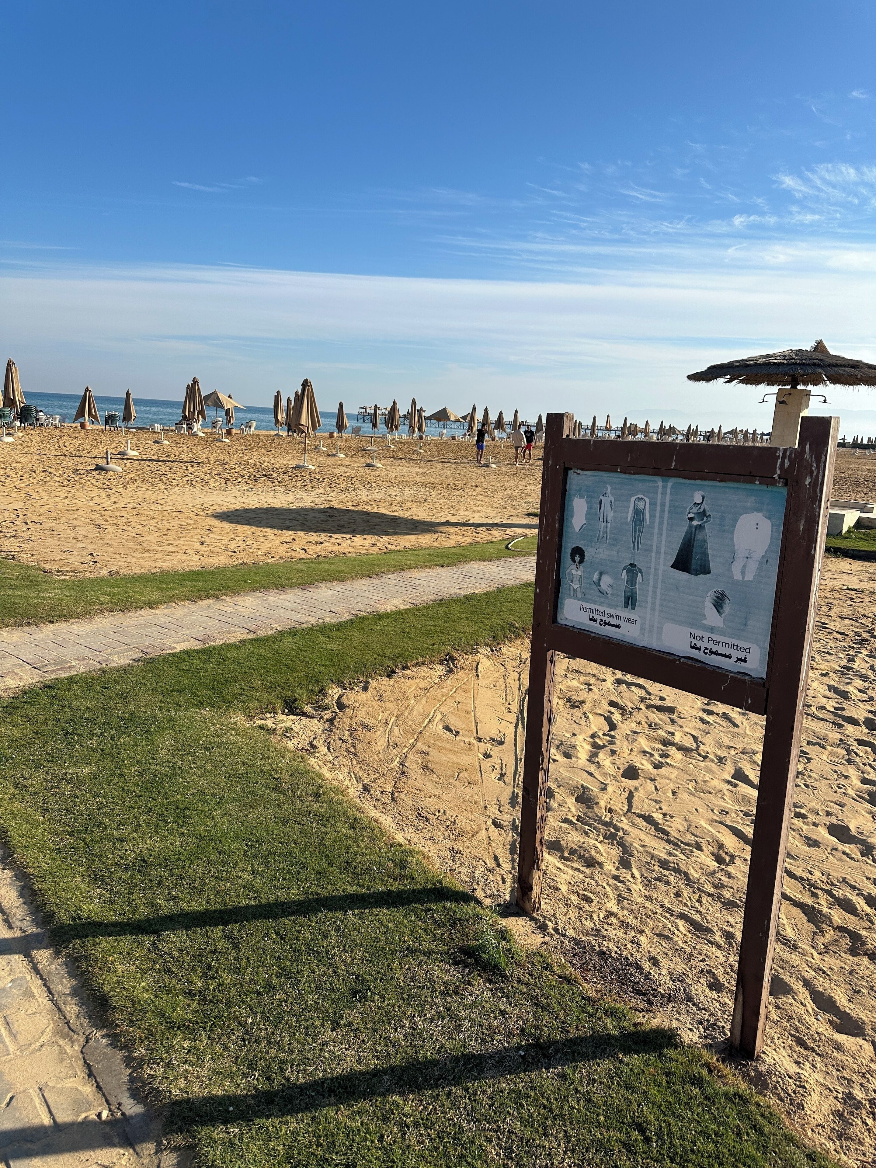Une plage où un panneau indique les types de maillots de bain autorisés et ceux qui ne le sont pas.