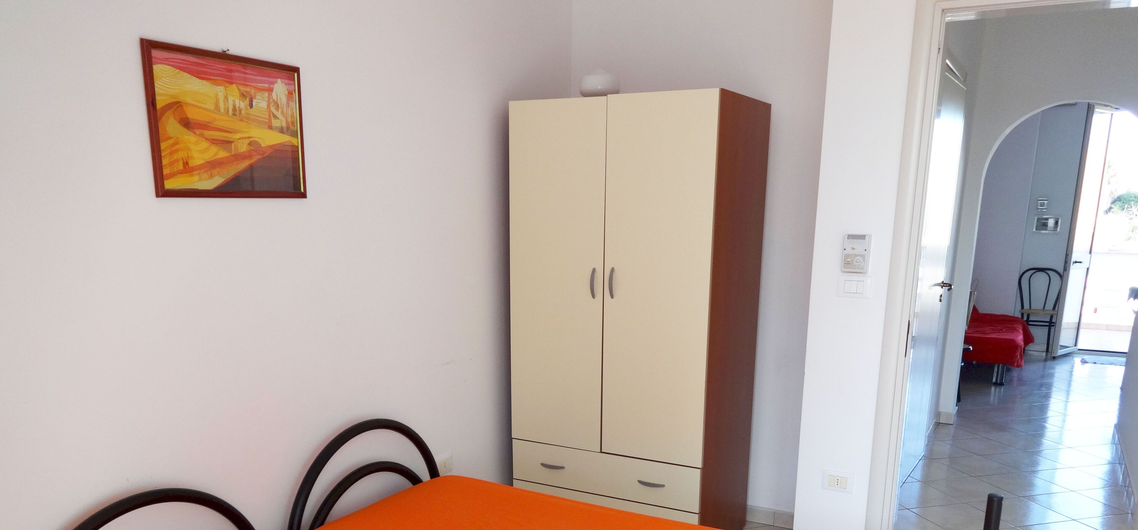 Una habitación con cama, armario, cuadro y mesa de comedor.