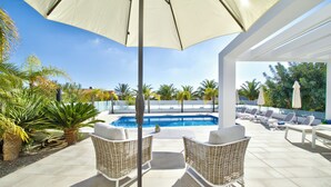 Et poolområde med fletstol, stor parasol og udsigt til swimmingpool.