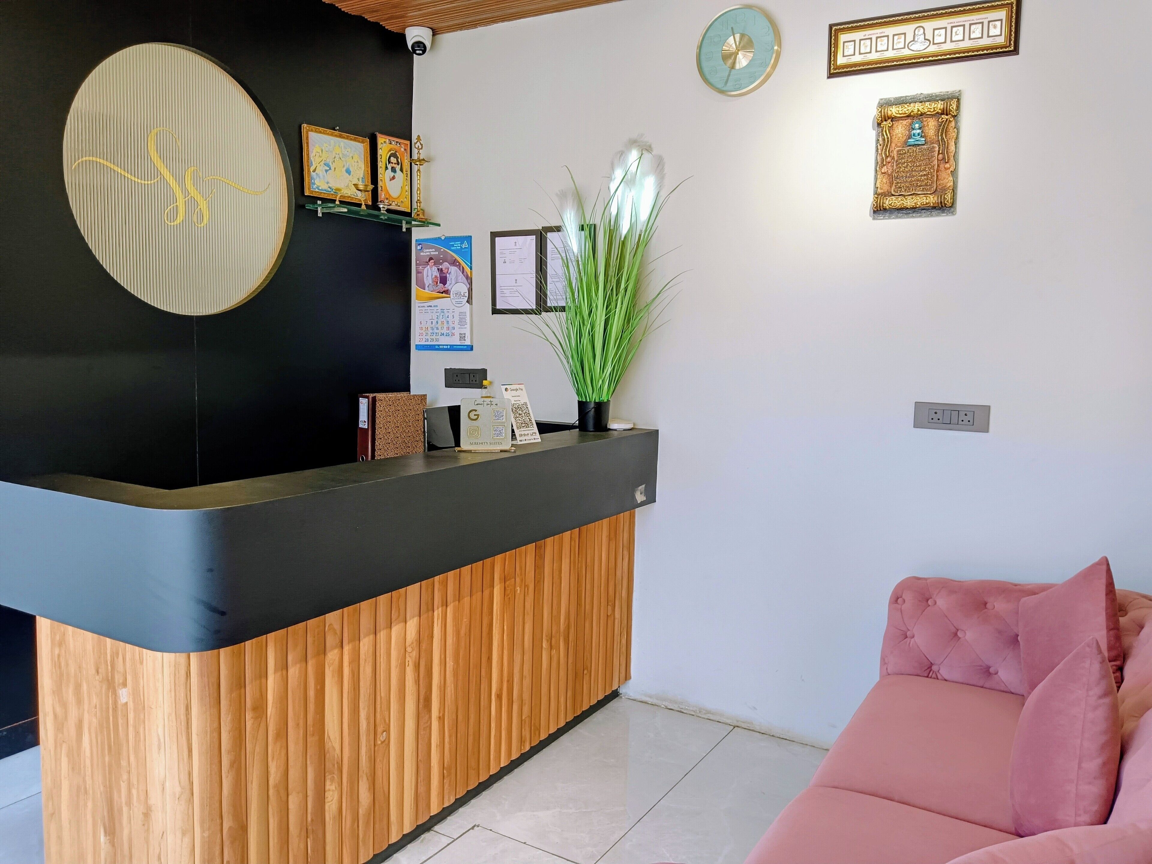 Un área de recepción con un mostrador de madera, un sofá rosa y varios objetos enmarcados en la pared.