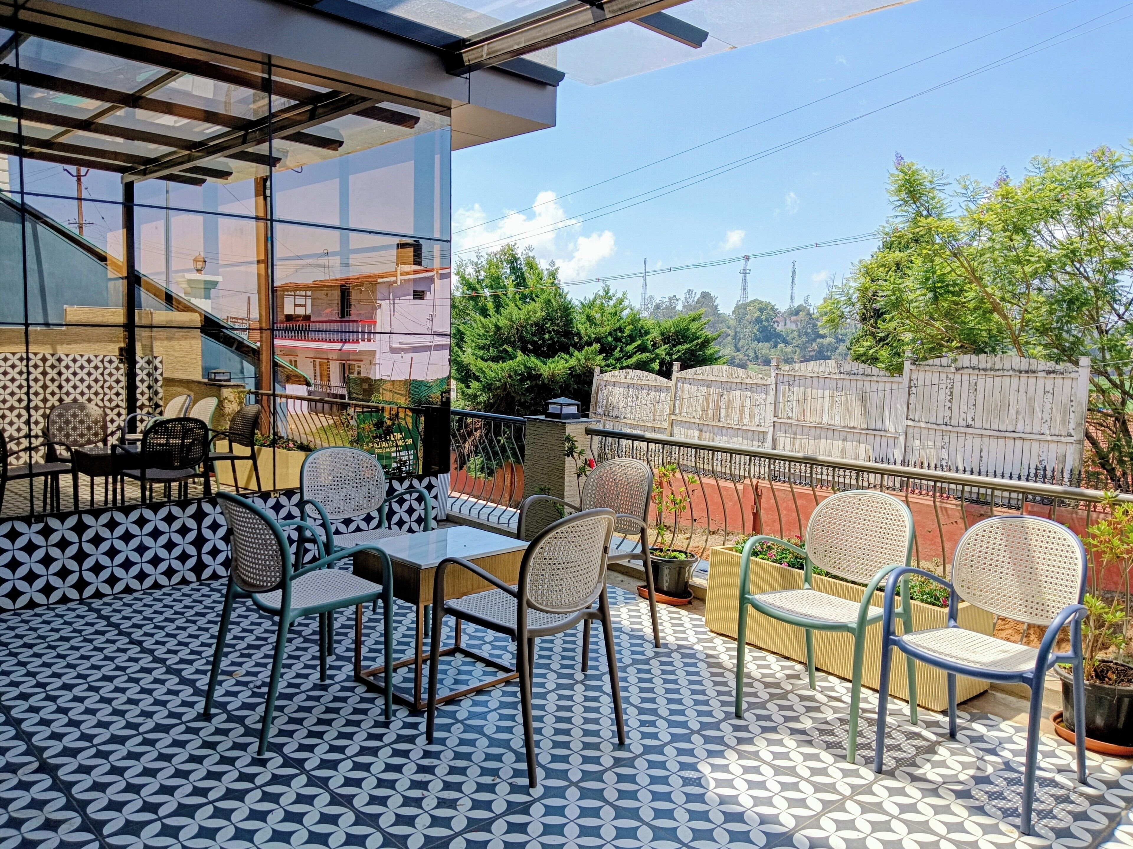 A terrace with patterned flooring, outdoor seating, and a view of a residential area.