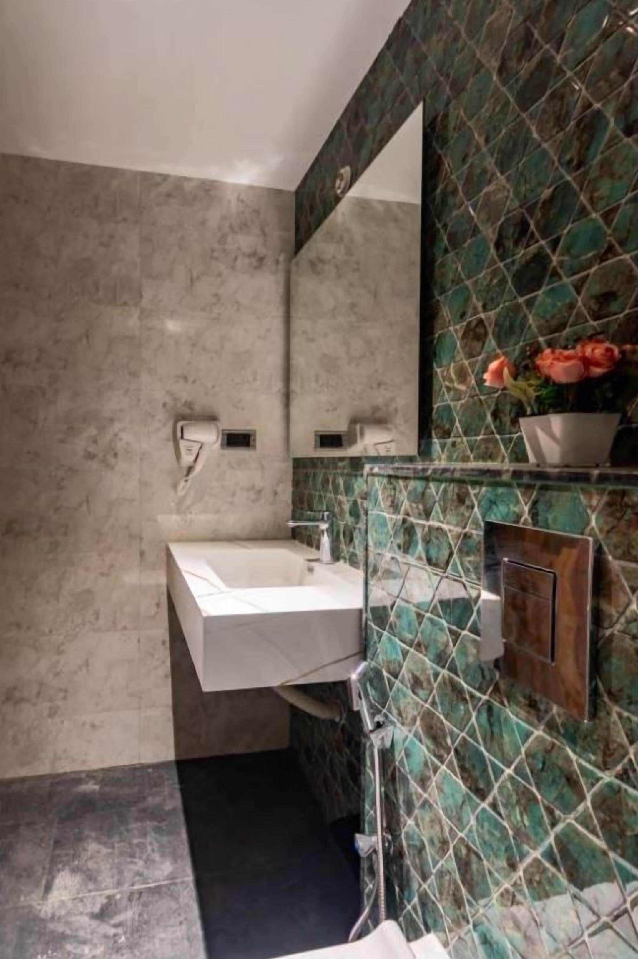 A bathroom with a white sink, a mirror, and a shower area.
