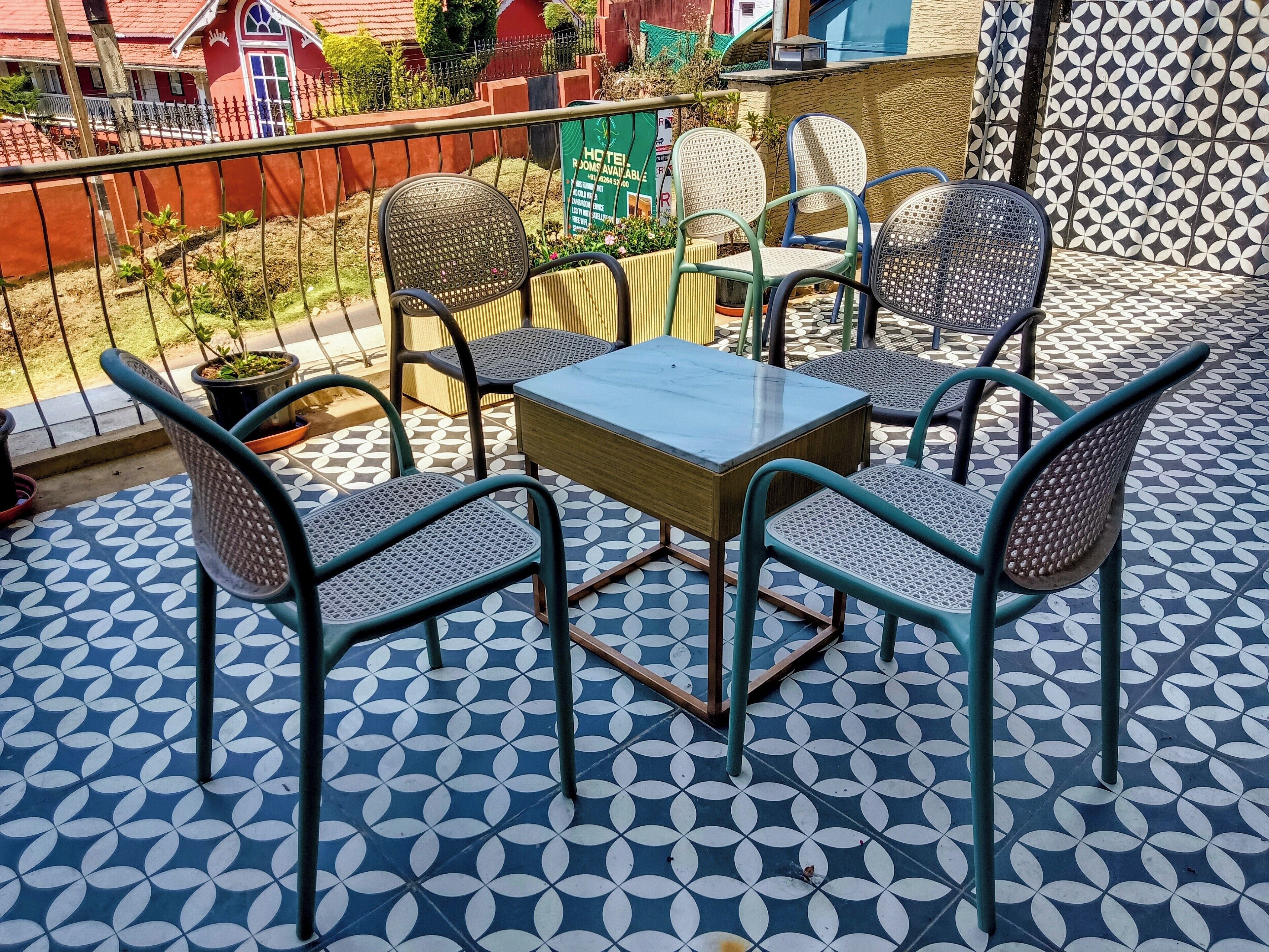 Una terraza con una mesa y cuatro sillas, un suelo estampado y vistas a un edificio rojo al fondo.