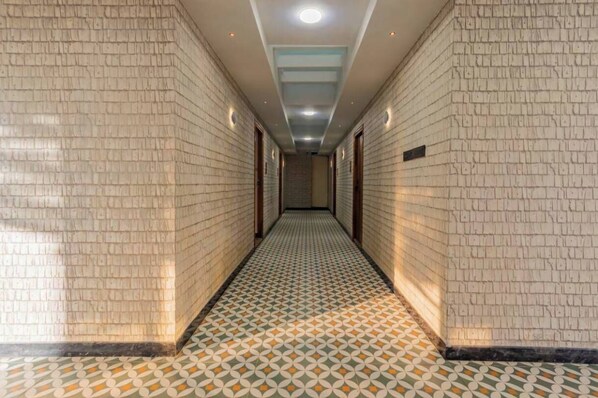 Un pasillo largo y estrecho con baldosas de diseño y paredes de ladrillo, que conduce a una escalera al final.
