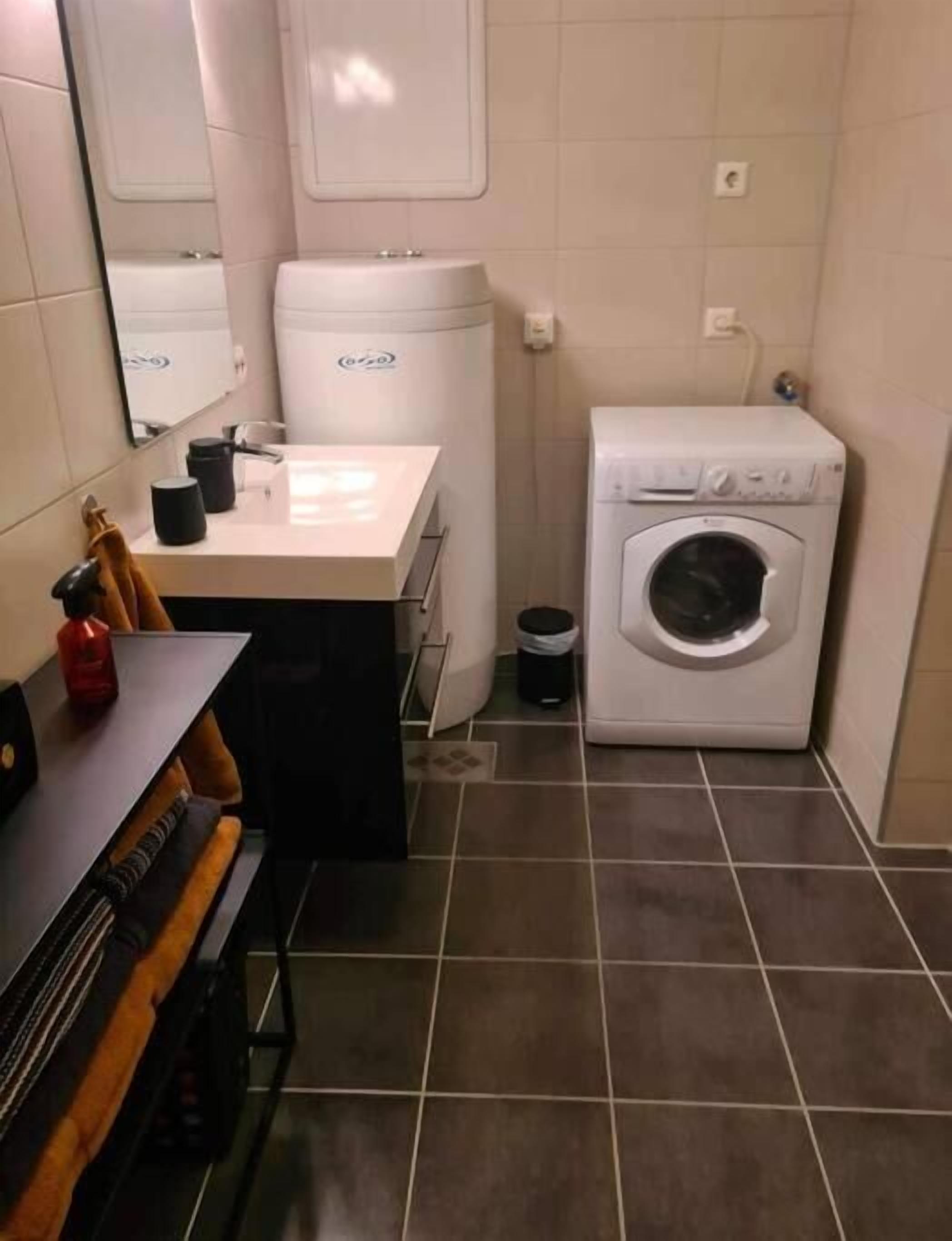 A compact bathroom with a sink, mirror, and a washing machine.