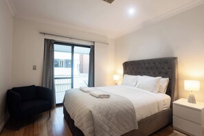 Una habitación de hotel con cama, una silla, una mesita de noche y una ventana con cortinas.