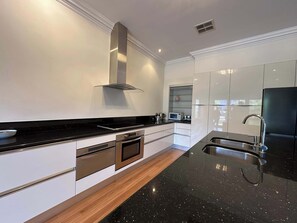 A modern kitchen with a black countertop, stainless steel appliances, and white cabinetry.