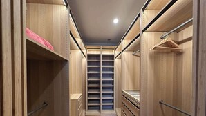 A narrow walk-through closet with wooden shelving and drawers, metal hangers, and a metal rod for hanging clothes. - Spacious 3 BDR family home with Parking and BBQ! (Perth)