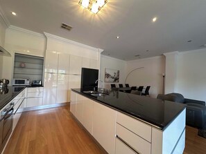 A modern kitchen with a central island, built-in appliances, and a dining area with a table and chairs.