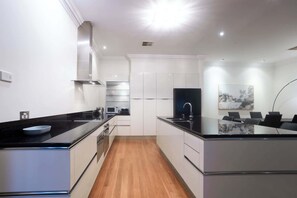 A modern kitchen with a central island, white cabinetry, and a wooden floor.