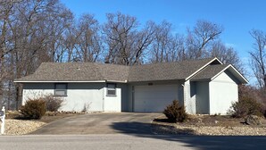 A single-story house with a garage, a front driveway, and a small front yard with shrubs.