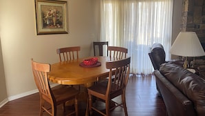 A dining area with a wooden table and chairs, a red basket, and a painting on the wall.
