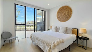 Un dormitorio moderno con una cama grande, un balcón con vistas y un adorno circular tejido en la pared.