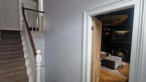 A staircase leading to a room with a fireplace, a television, and a dog resting on a rug.