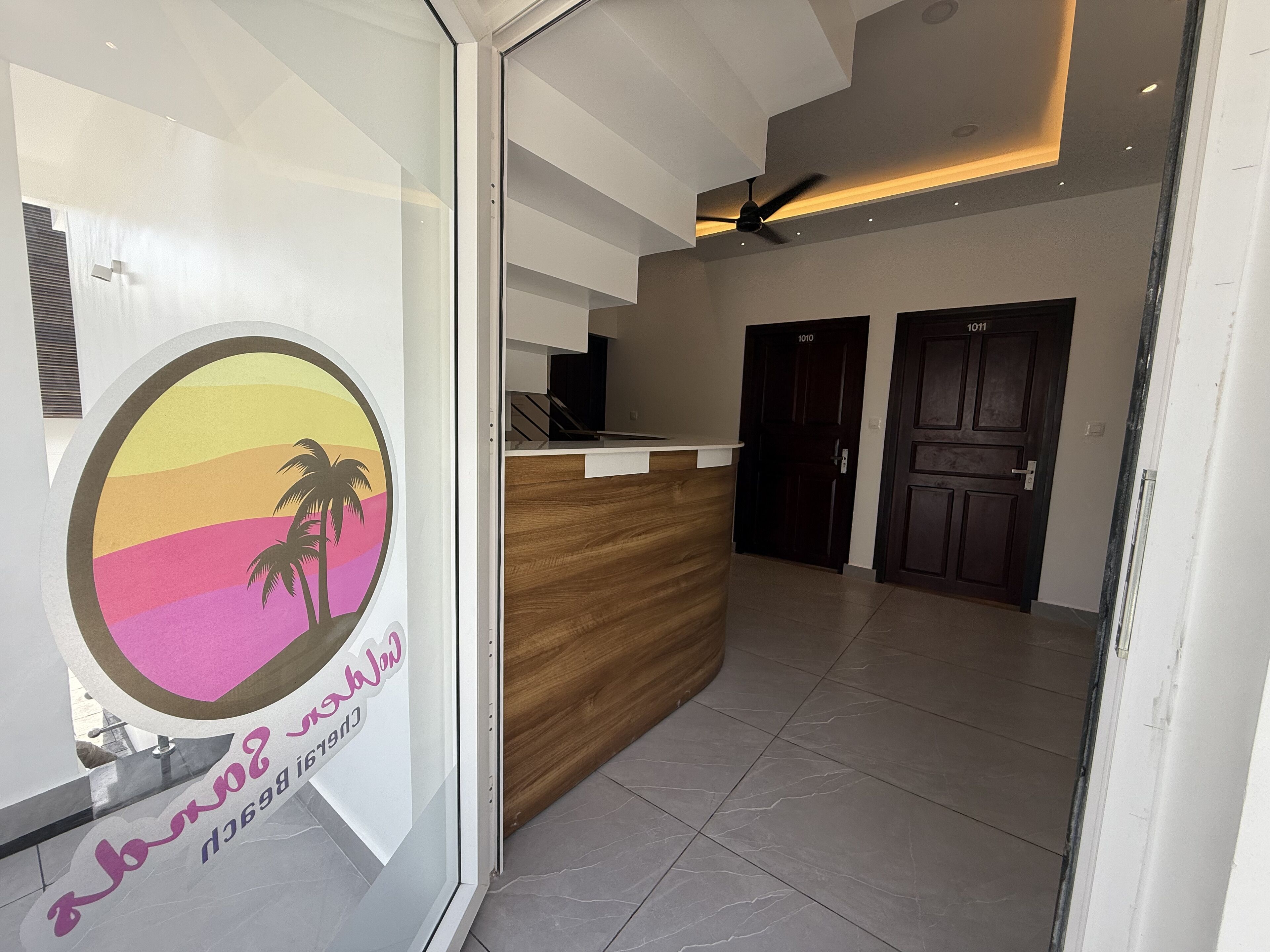 A reception area with a wooden counter, two dark doors, and a glass wall with a circular logo.