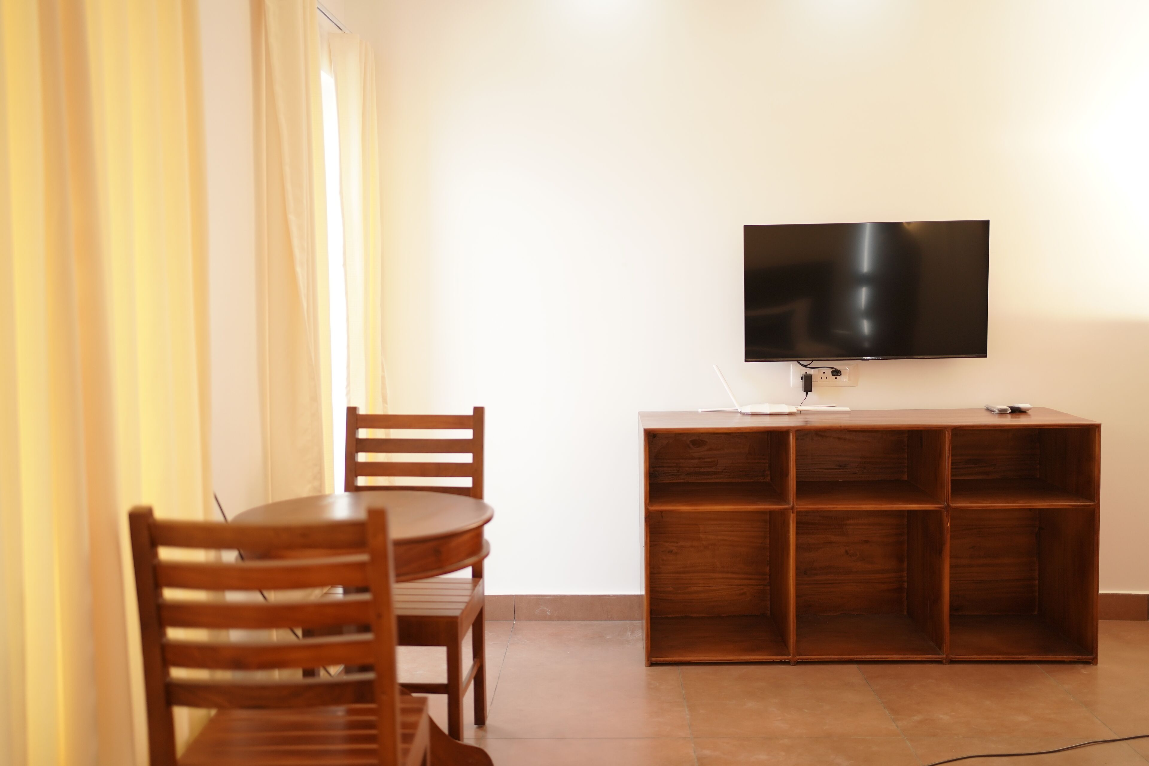Un coin repas avec une table et des chaises en bois, un téléviseur fixé au mur et un meuble en bois en dessous.