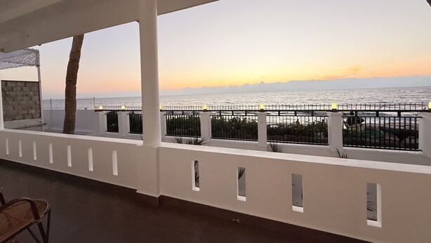 A balcony with a view of the sea at sunset. - Golden Sands Cherai (Kochi)