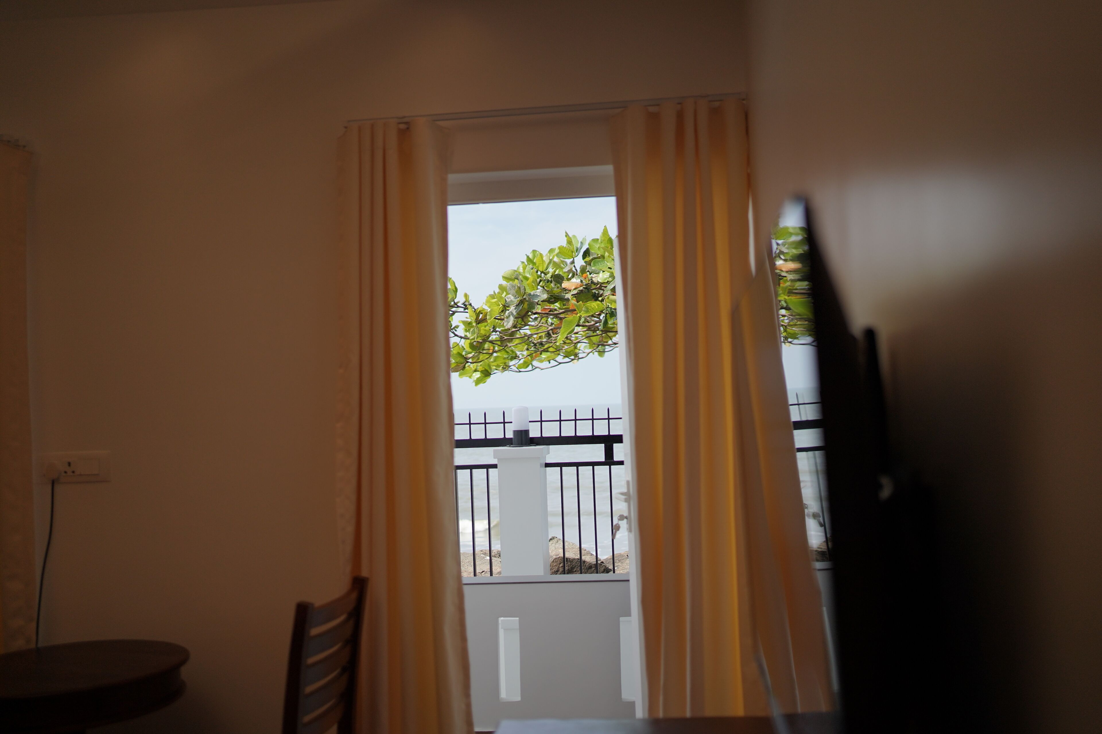 A room with a view of a balcony, a dining table, and a chair.