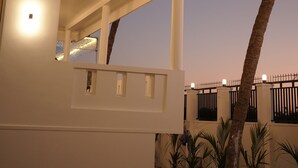 A modern building with a flat roof, multiple windows, and a palm tree in the foreground. - Golden Sands Cherai (Kochi)