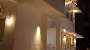 A modern two-story building with a balcony, illuminated exterior lighting, and a staircase leading to the upper floor. - Golden Sands Cherai (Kochi)