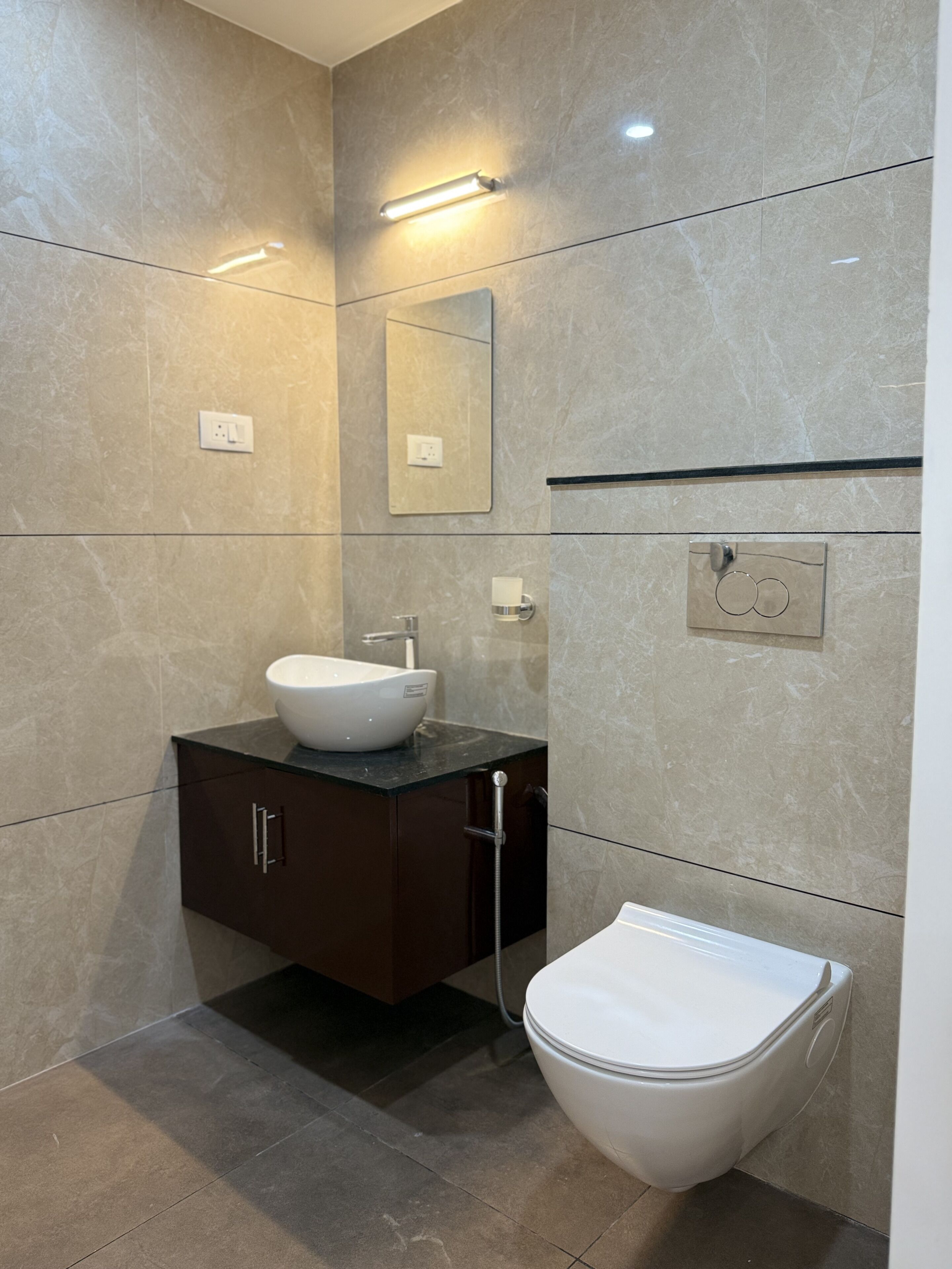 Un baño moderno con un lavamanos blanco, un mueble de almacenamiento oscuro y un inodoro.