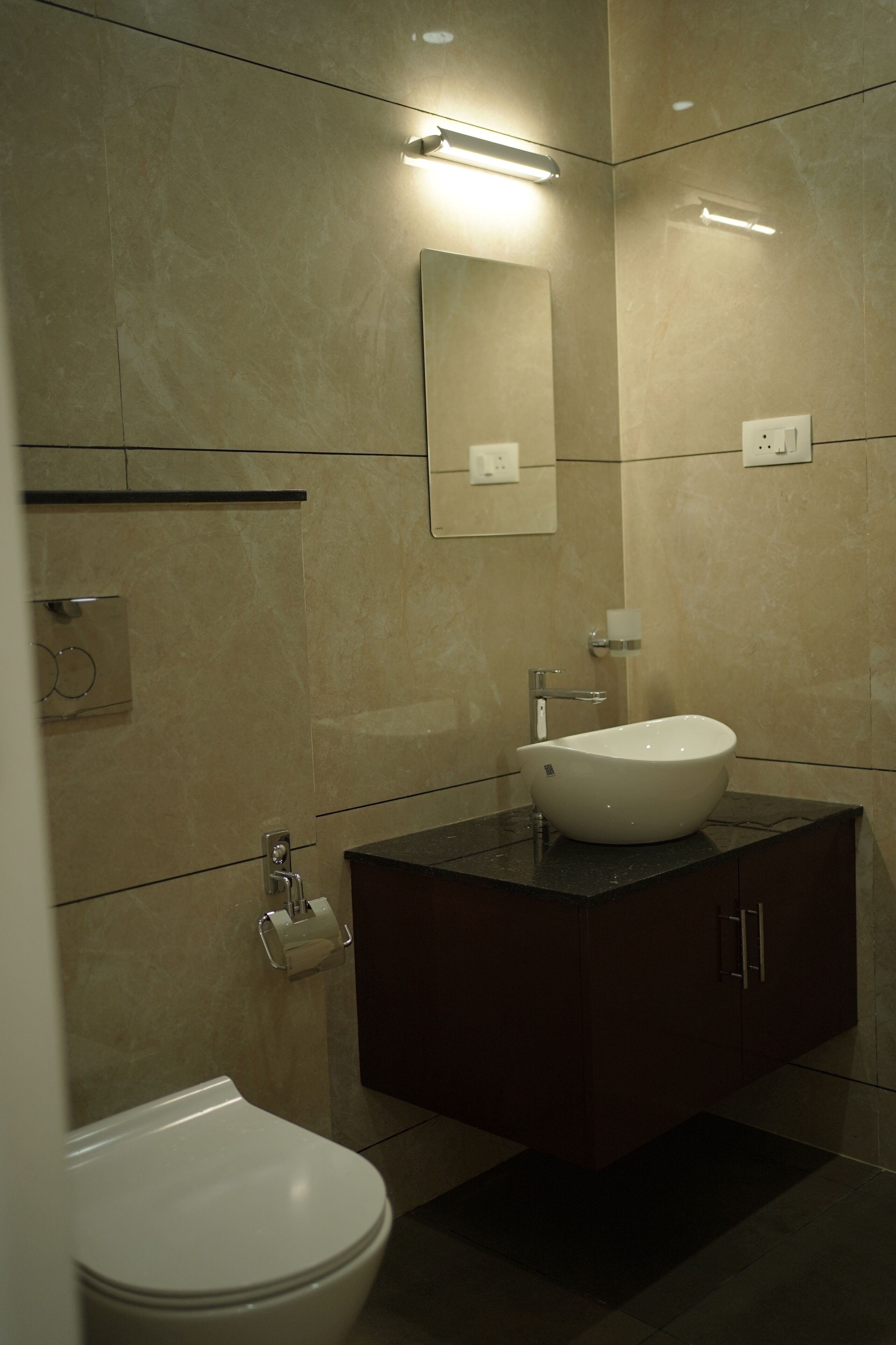 A modern bathroom with a white sink, dark vanity, and a mirror above the sink.