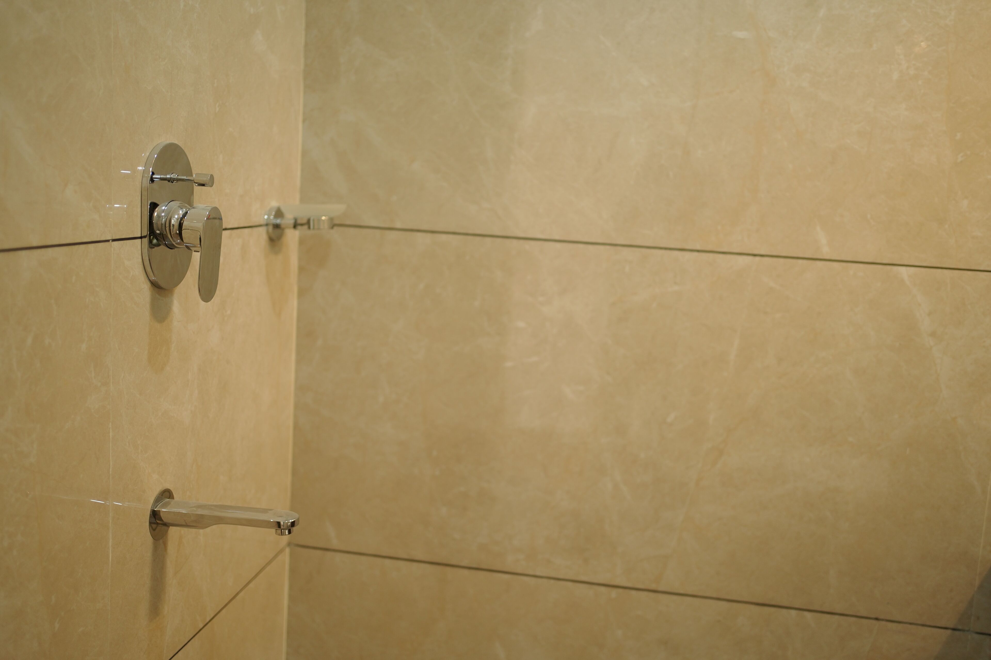 A bathroom with a marble wall, a shower with a glass door, and a towel rack.