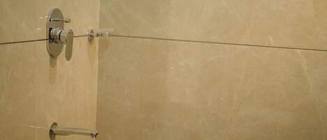 A bathroom with a marble wall, a shower with a glass door, and a towel rack.