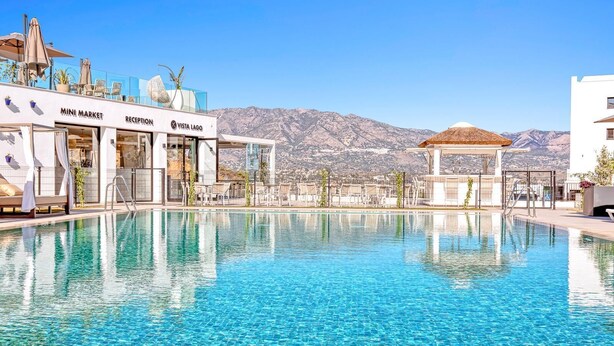 Piscina con zona de recepción y vista a la montaña.