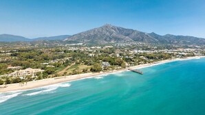 Un pueblo costero con montaña, playa y muelle.