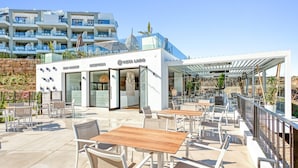 Un bar en la azotea con mesas al aire libre y vistas al mar.