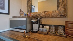 A kitchenette with a microwave, coffee maker, and a tray with water bottles and glasses. - Charming waterfront hotel in serene Suffolk with WiFi, AC (Suffolk)