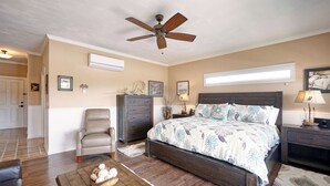 A bedroom with a large bed, a ceiling fan, a dresser, a chair, and a nightstand with a lamp. - Charming waterfront hotel in serene Suffolk with WiFi, AC (Suffolk)