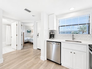 A modern kitchen with white cabinets, a dishwasher, and a coffee maker. - Coastal Beachfront Oasis | Prime Spot (St. Pete Beach)