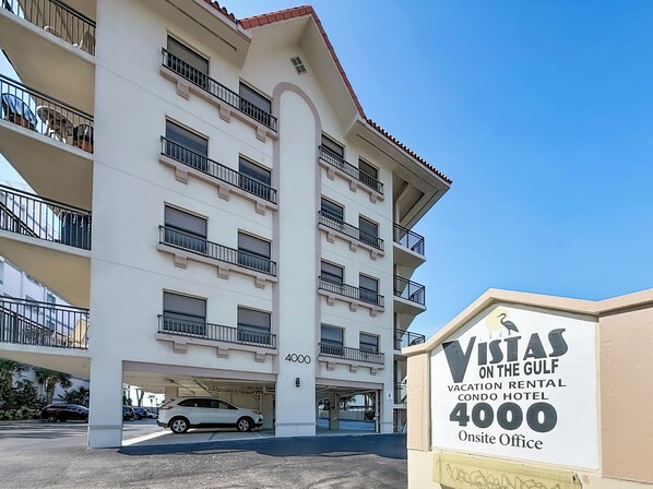Un immeuble à plusieurs étages, doté de balcons et d’une enseigne indiquant qu’il s’agit d’un hôtel proposant des appartements de location pour les vacances, nommé « Vistas on the Gulf », situé au 4000.