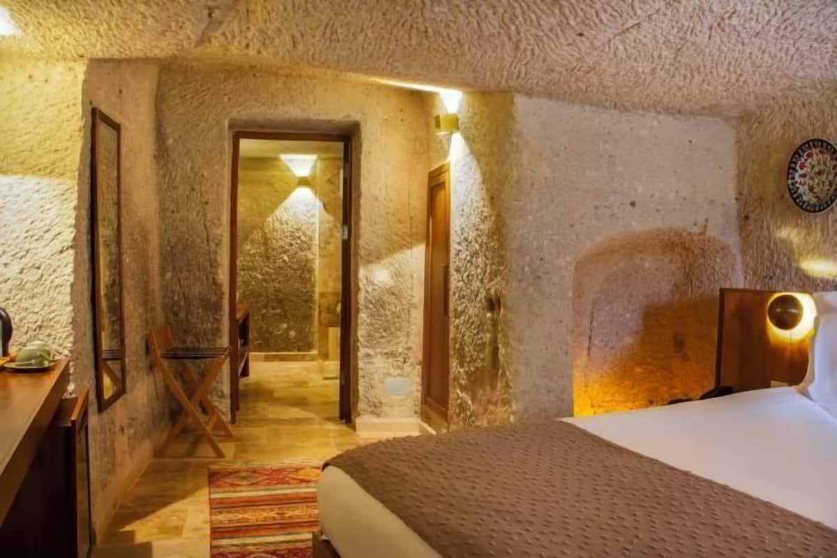 Un dormitorio con cama, escritorio, silla y puerta que da a otra habitación.