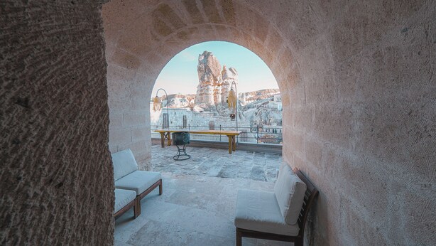Une pièce aux murs de pierre, donnant sur un paysage rocheux, avec une table et deux chaises.
