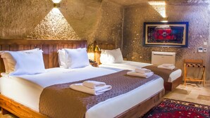 Une chambre avec deux lits, des têtes de lit en bois, un téléviseur fixé au mur et un tapis rouge à motifs.
