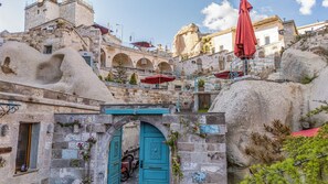 A historic stone building with a turquoise door, a staircase, and a red umbrella. - Logos Cave Cappadocia (Nevsehir)