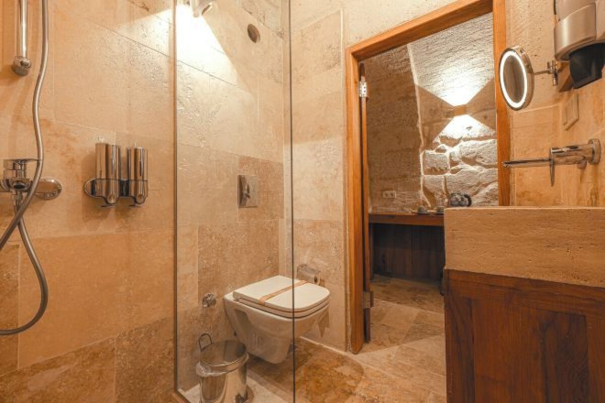 Une salle de bain avec une douche à parois de verre, des toilettes et un meuble-lavabo en bois avec un miroir.
