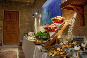 A buffet with various food items, a wooden door, and a wall-mounted painting. - Logos Cave Cappadocia (Nevsehir)